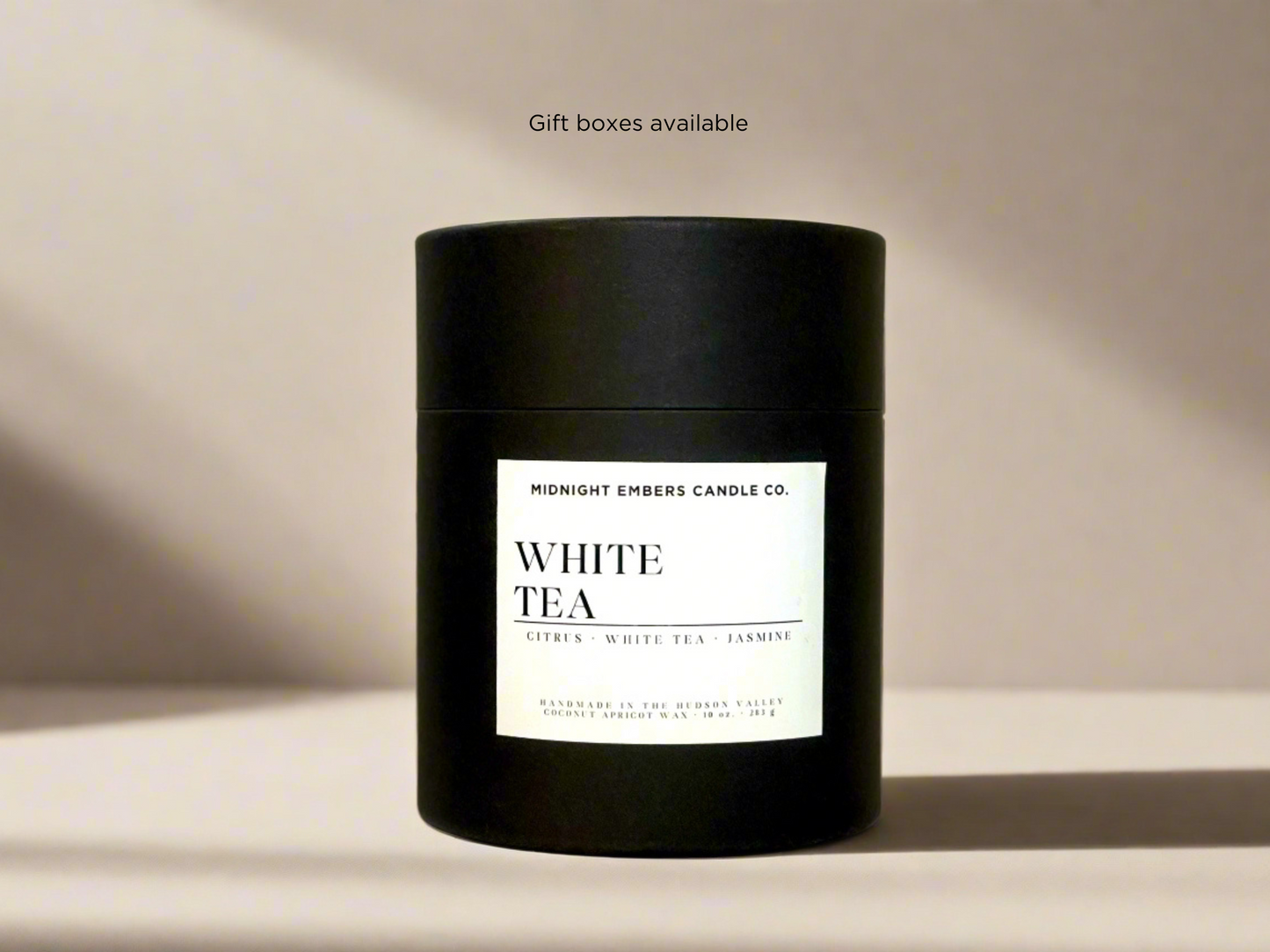 Black candle with 'White Tea' label on a beige background