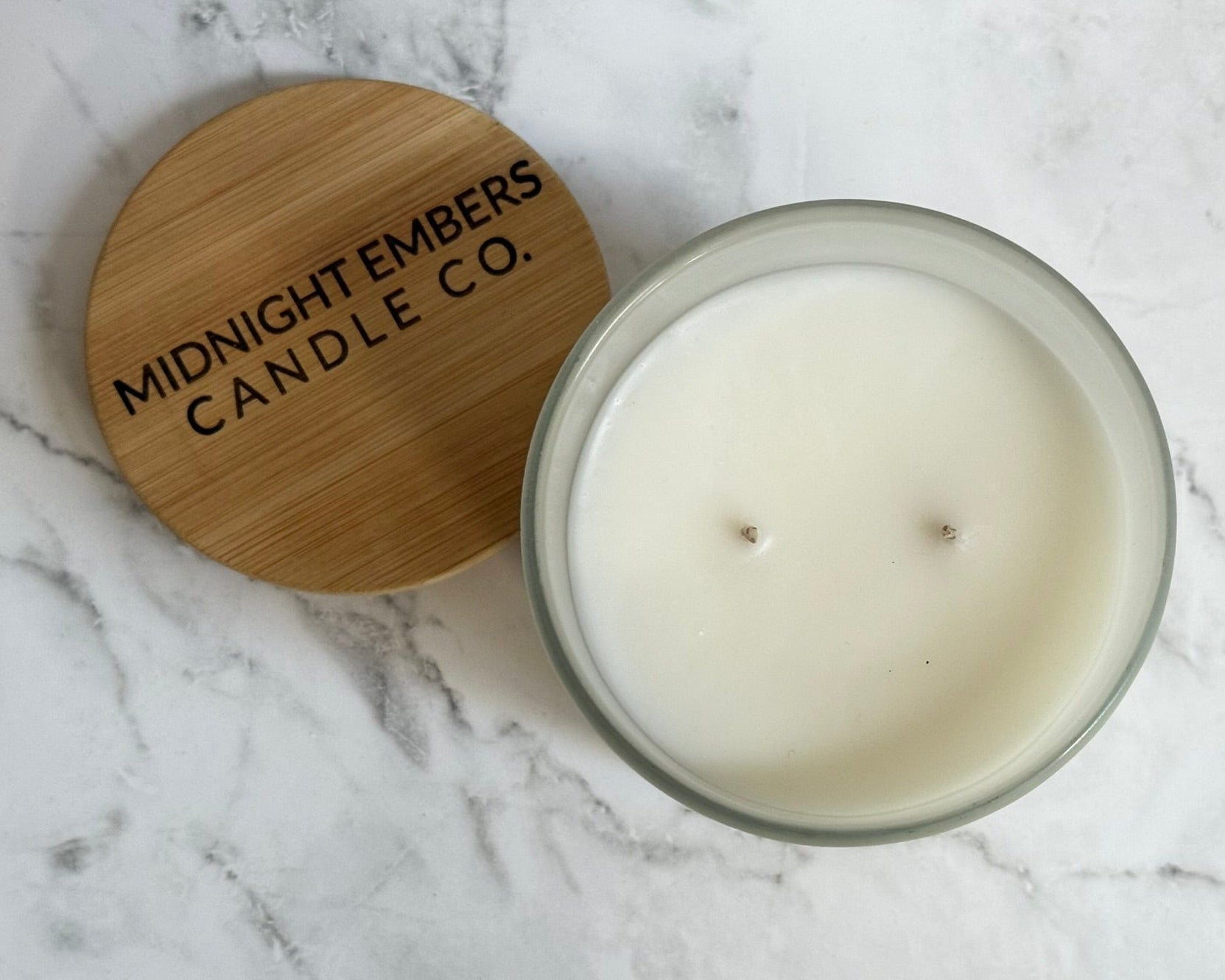Candle with wooden lid on a marble surface, featuring 'Midnight Embers Candle Co.'