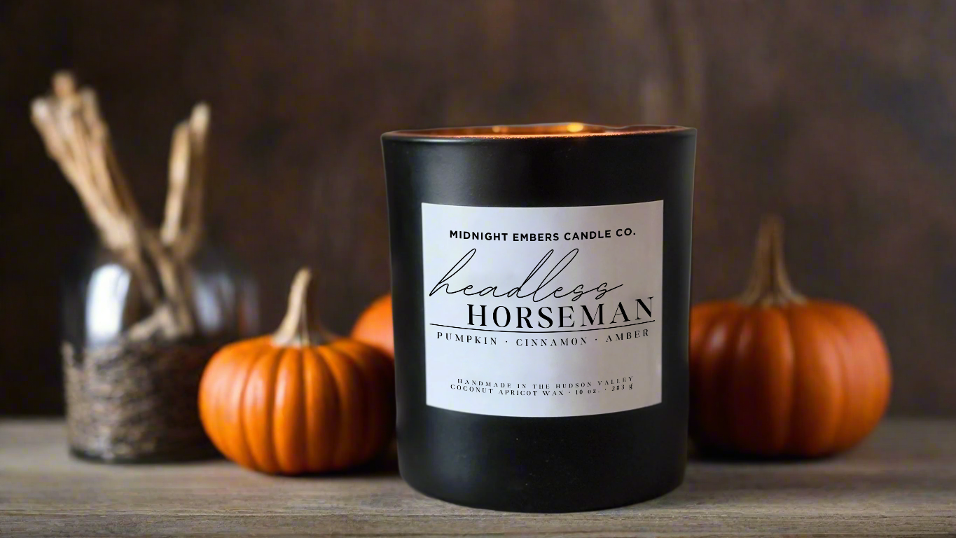 Black candle labeled 'Headless Horseman' with pumpkins and twigs in the background