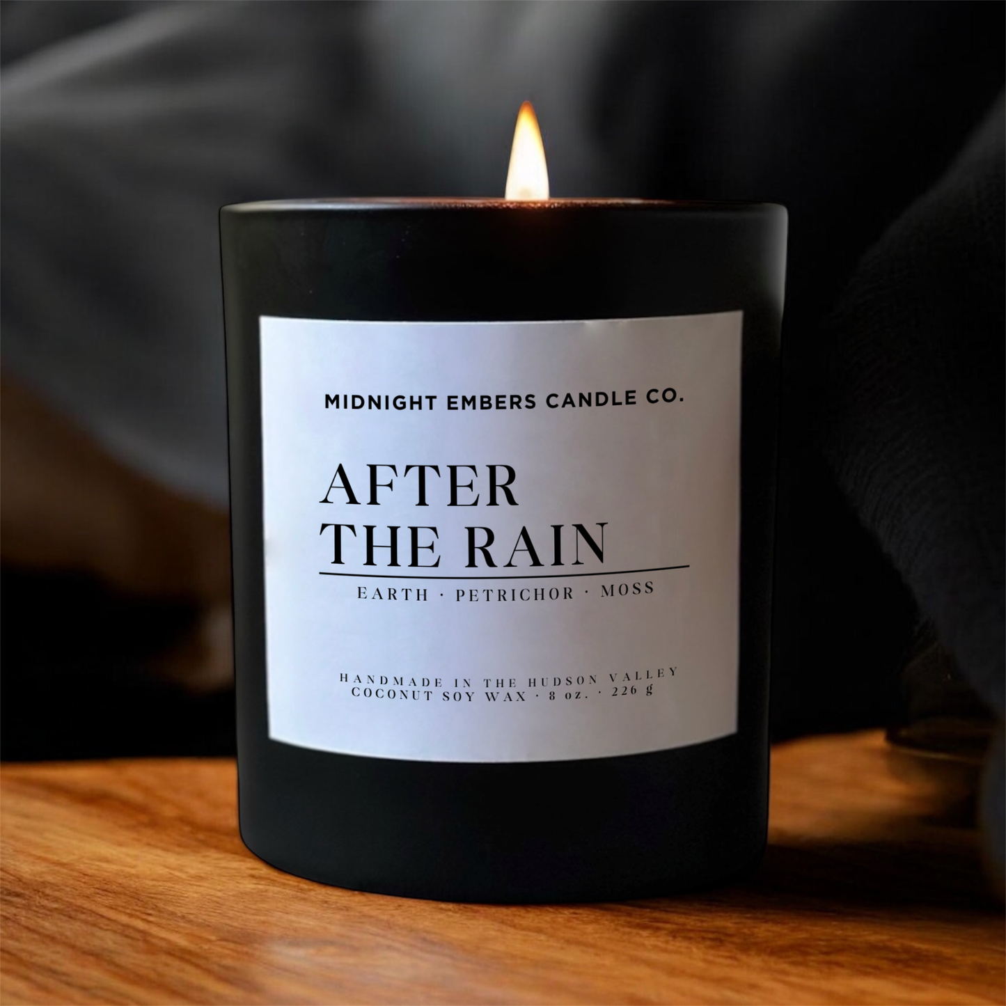 Candle with 'After the Rain' label from Midnight Embers Candle Co. on a wooden surface.