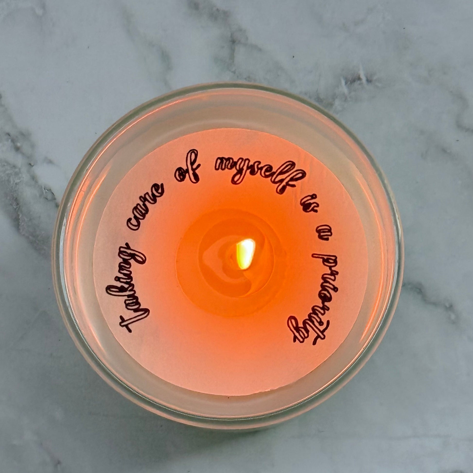 Candle in a glass jar with text on a marble surface