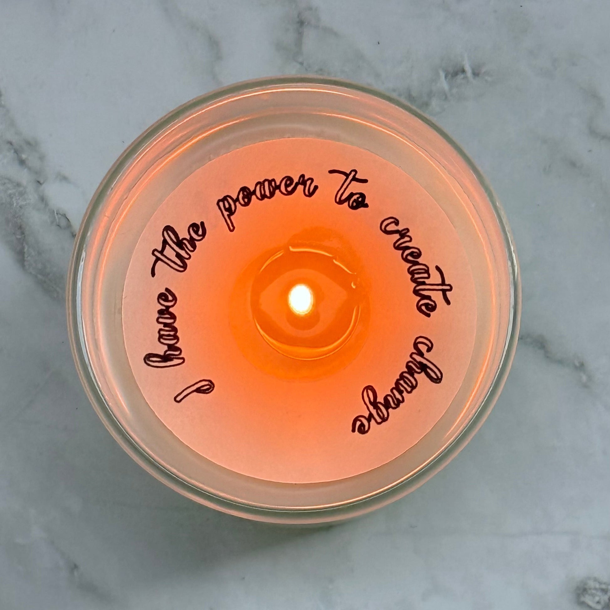 Candle with a motivational quote on a marble surface