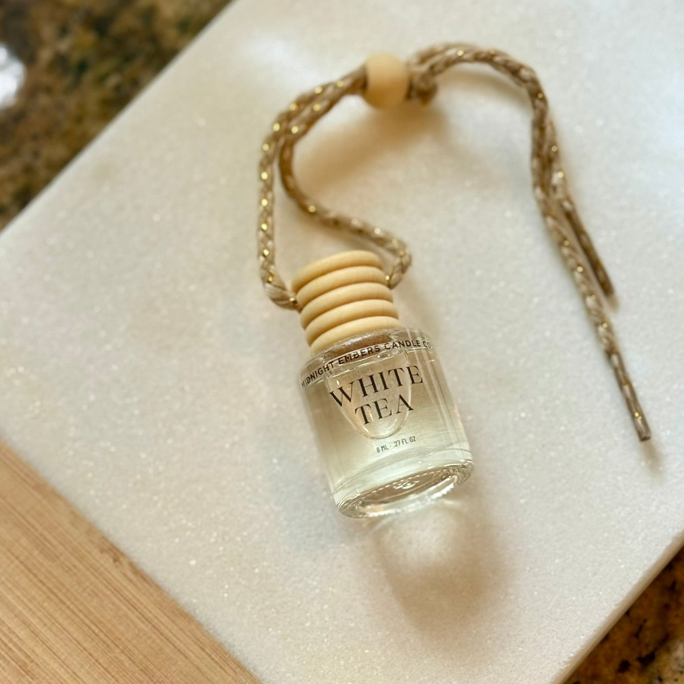 Small bottle labeled 'White Tea' with wooden cap on a textured surface