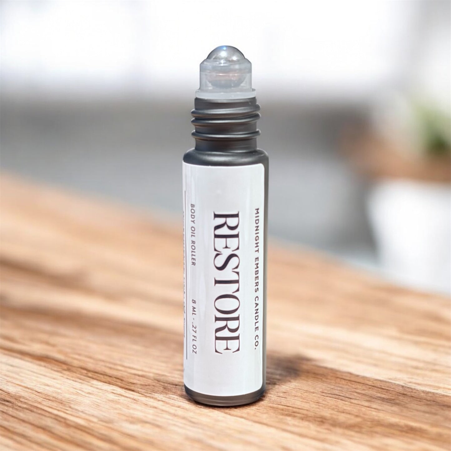 Roll-on bottle labeled 'RESTORE' on a wooden surface with a blurred background