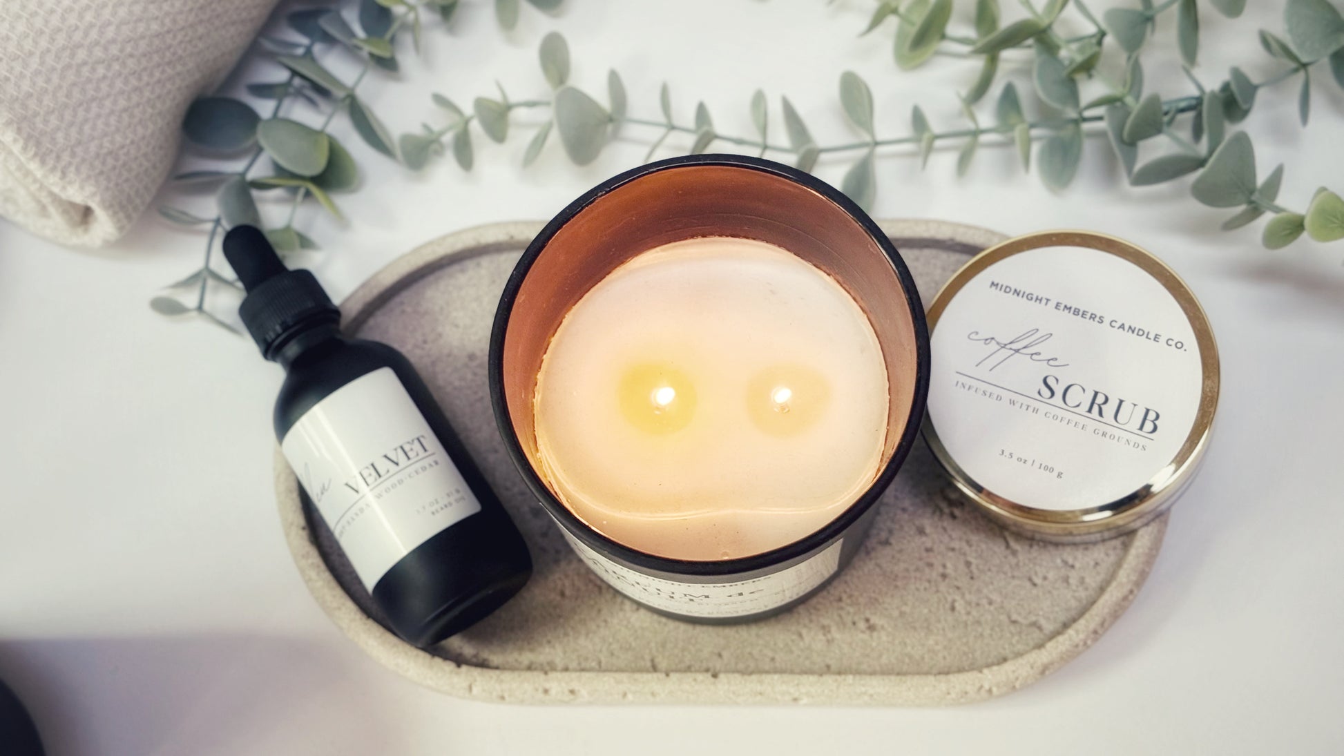 Candle, bottle, and jar on a tray with eucalyptus leaves in the background