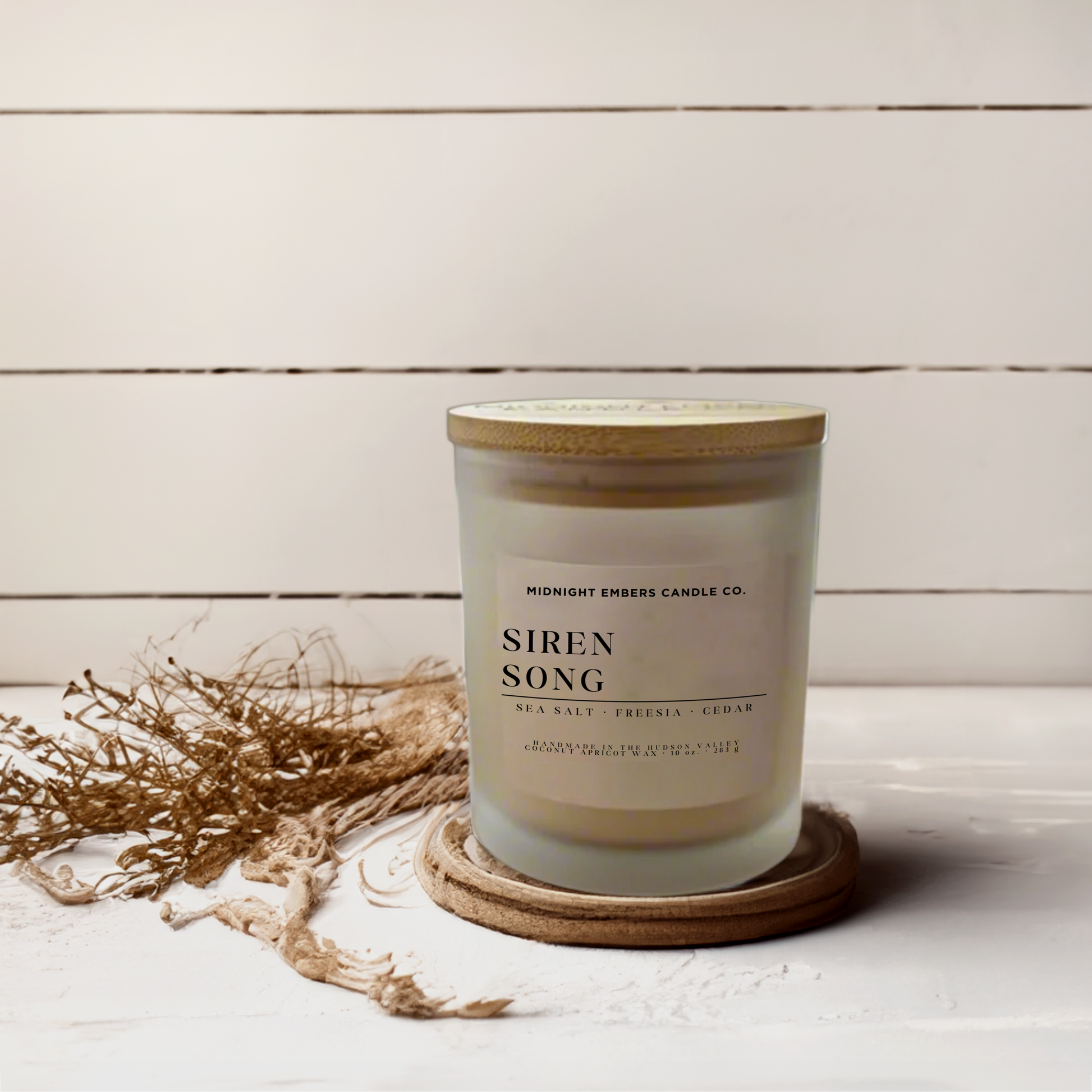 Candle with 'Siren Song' on a wooden coaster against a light wooden background