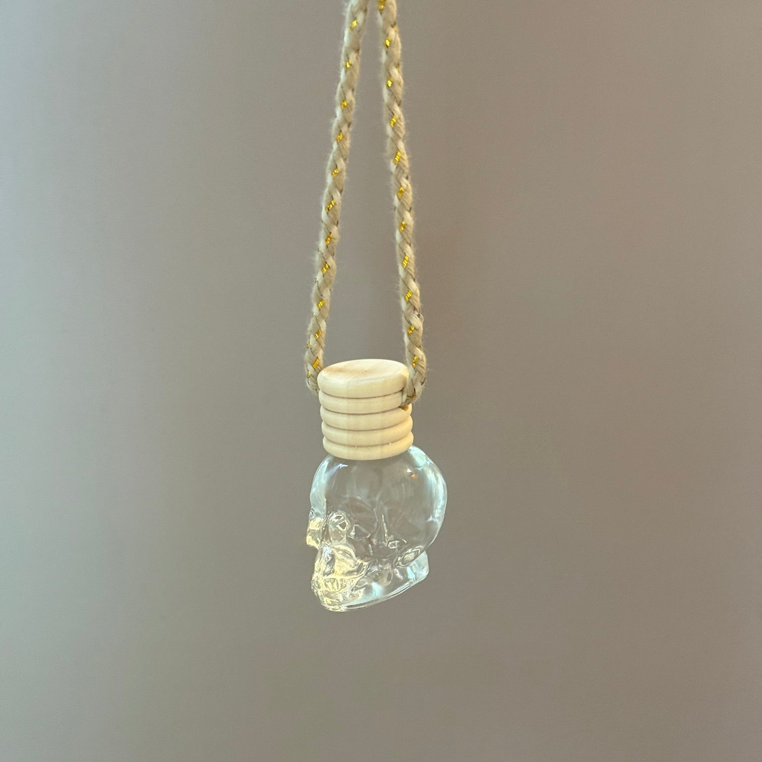 Glass pendant with skull design on a chain against a plain background
