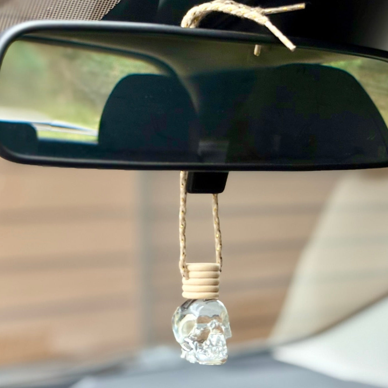 Car air freshener shaped like a crystal skull hanging from a car's rearview mirror.