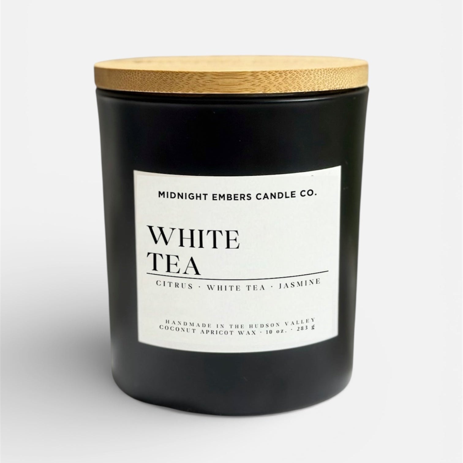 Black candle with a wooden lid labeled 'White Tea' from Midnight Embers Candle Co.
